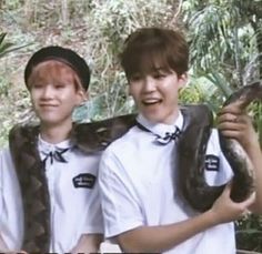 two young men are holding snakes in their hands