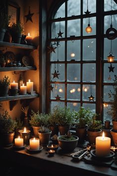 a table topped with lots of potted plants next to a window filled with lit candles