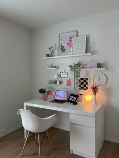 a white desk topped with a laptop computer next to a chair and wall mounted clock