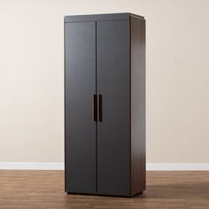 a tall black cabinet sitting on top of a hard wood floor next to a white wall