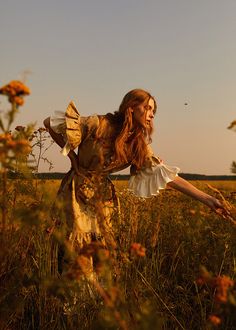 a woman standing in a field with her arms outstretched