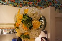 a vase filled with yellow and white flowers on top of a table next to a mirror