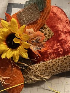 a sunflower sitting on top of a piece of fabric next to an orange pillow