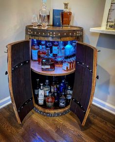 a wooden barrel filled with liquor bottles on top of a hard wood floor next to a wall