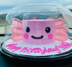 a pink cake with an angel design on it's face in a glass dome