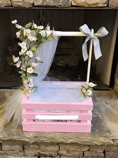 a pink and white box with flowers on it sitting in front of a fire place