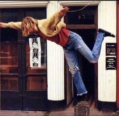 a person jumping up into the air with their legs in the air while wearing jeans and a sweater