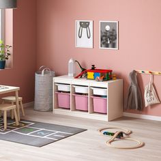 a child's room with pink walls and toys on the floor