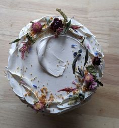 a white cake with flowers on it sitting on a wooden counter top next to a knife and fork