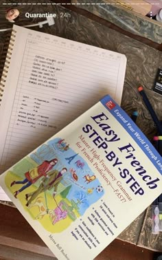 a book sitting on top of a wooden desk next to some pens and pencils