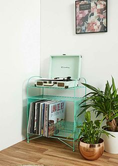 a record player sitting on top of a green shelf next to a potted plant