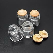 four jars with wooden lids are sitting on a black surface next to some cut up cookies