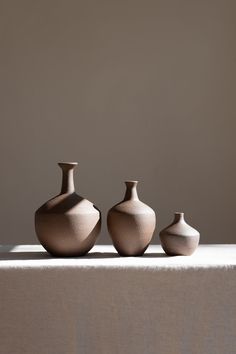 three brown vases sitting on top of a table