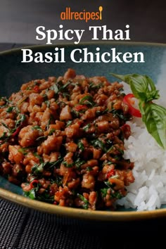 a blue bowl filled with rice and meat on top of a wooden table next to a green leafy garnish