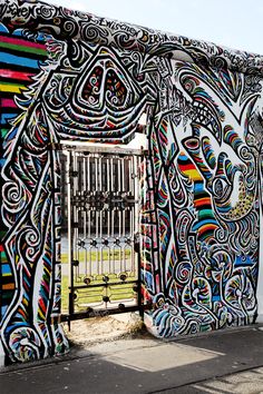 an artisticly painted wall with a gate and fence