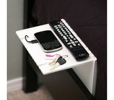 a green table with a cell phone and remote control on it next to a black bed