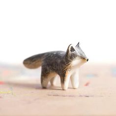 a small toy fox is standing on the ground with its tail up and eyes closed