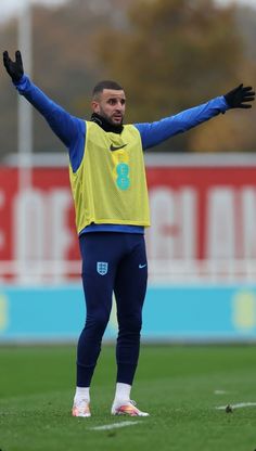 a man standing on top of a soccer field holding his arms up in the air