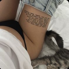 a woman laying on top of a bed with her stomach covered by a small tattoo