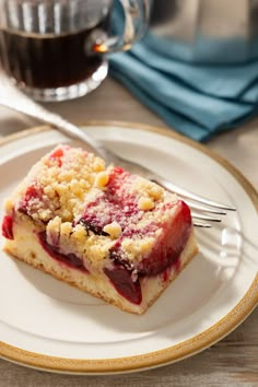 a piece of cake sitting on top of a white plate next to a cup of coffee