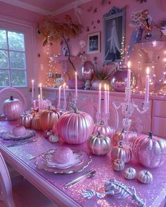 the table is set with pink and silver pumpkins, candles, and other decorations