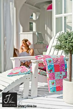 a woman sitting on a porch next to a white chair