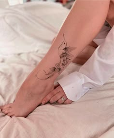 a woman's foot with a bird tattoo on it