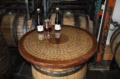 three bottles of wine sitting on top of wooden barrels