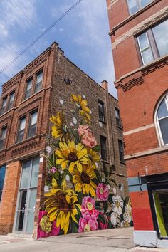 a large mural on the side of a building in front of a tall brick building