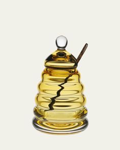 a glass honey jar with a wooden stick sticking out of it's top, on a white background