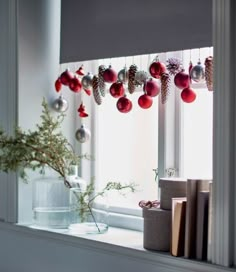 a window sill with ornaments hanging from it's windowsill and books on the ledge