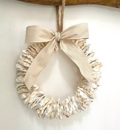 a white wreath hanging on a wooden branch