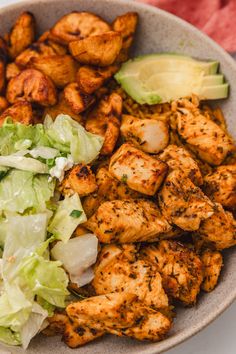 a bowl filled with chicken, lettuce and other food on top of a table