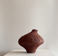 a brown vase sitting on top of a white table