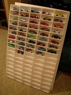 a toy car storage unit with cars on the top and bottom shelves filled with toys