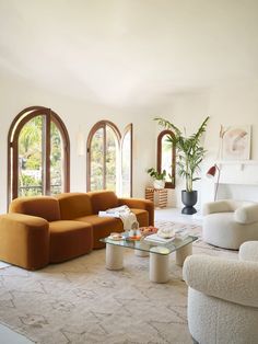 a living room filled with lots of furniture and large arched windows in the wall behind it