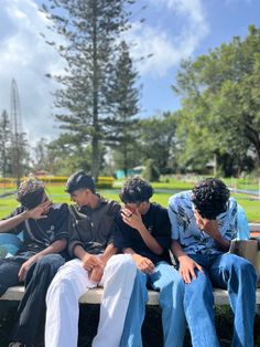 four young men sitting on a park bench