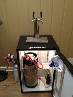 a small refrigerator with a beer keg inside of it next to other items on the floor