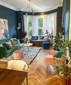 a living room filled with lots of furniture and plants on top of wooden flooring