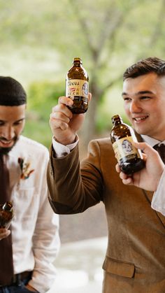 two men in suits holding up beer bottles