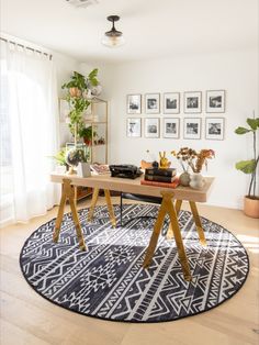 a living room with a rug, table and pictures on the wall