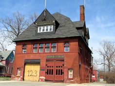 an old red brick building with a black roof and two story windows on the second floor