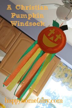 there is a paper decoration hanging from the ceiling in this kitchen with words above it that read, a christian pumpkin windsock