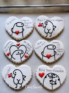 four decorated cookies in the shape of hearts with words written on them and two birds