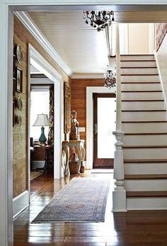 an entry way with stairs and chandelier in the center, along with a rug on the floor