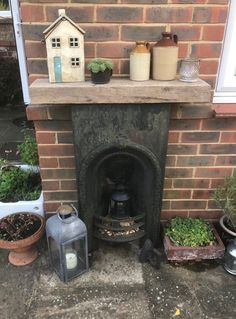 a brick fireplace with pots and plants on it next to a small house shaped window