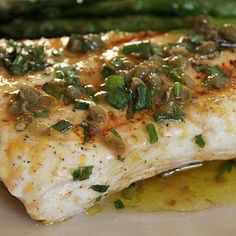 a white plate topped with fish and asparagus