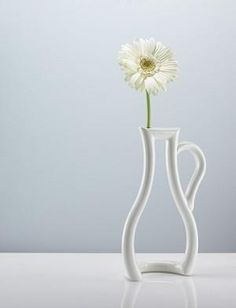 a white vase with a flower in it