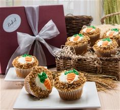 several carrot cupcakes are sitting on a plate next to a box of treats