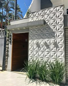 a white building with an intricate design on the front and side wall, next to some plants